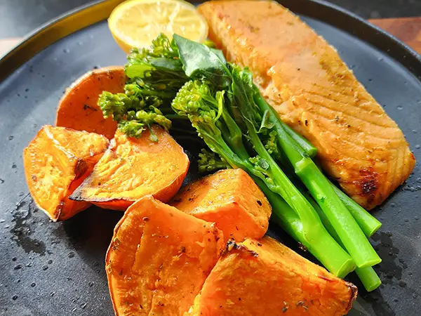 Baked salmon with sweet potatoes and tenderstem broccoli on the black plate