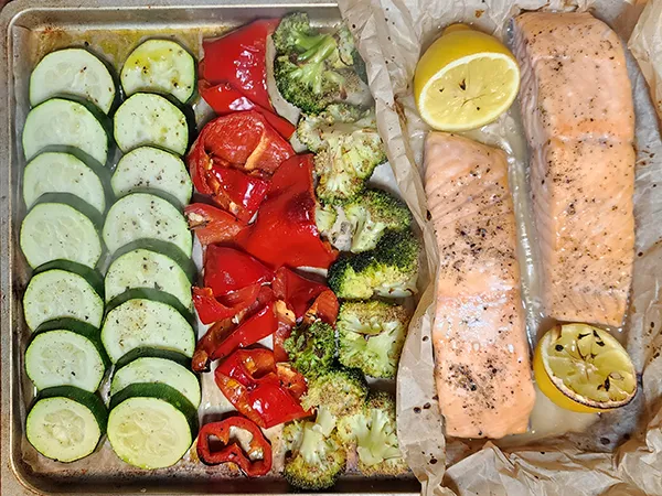 Cooked vegetables and salmon fillets on the baking tray