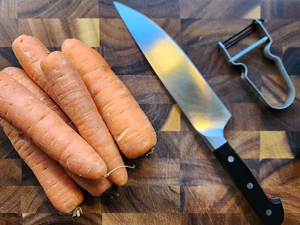Carrots and a knife on a wooden board. How to dice carrots