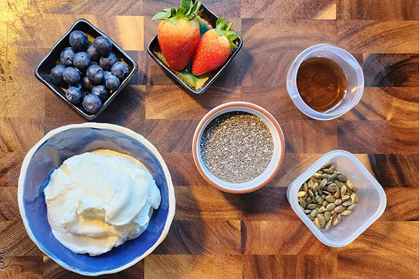 Greek yogurt, maple suryp. chia seeds and berries on the wooden board