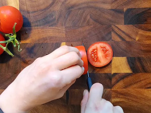 Slicing tomato on the wooden board