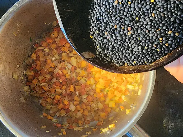 Stiring up the lentil soup and adding spices. How to cook legumes