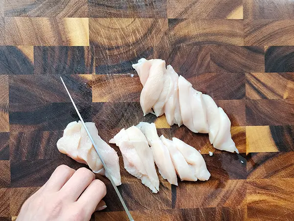 Slicing raw chicken fillets