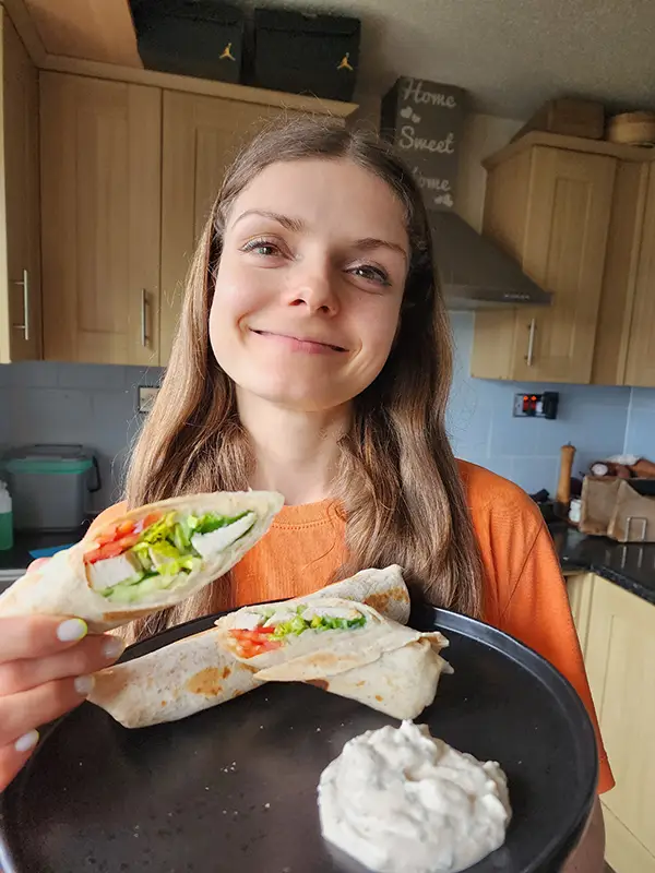 Smiling woman with chicken wraps in hans