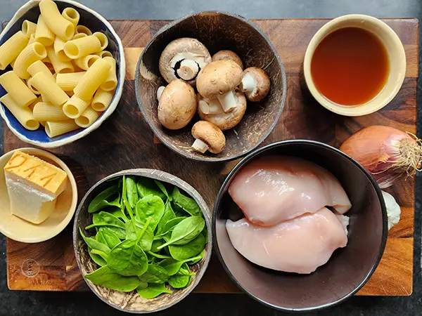 Chicken, myshroom, spinach pasta ingredients on the wooden board