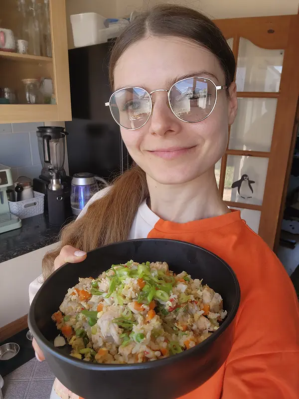 Young woman  with a bowl of hot frshly made chicken fried rice.